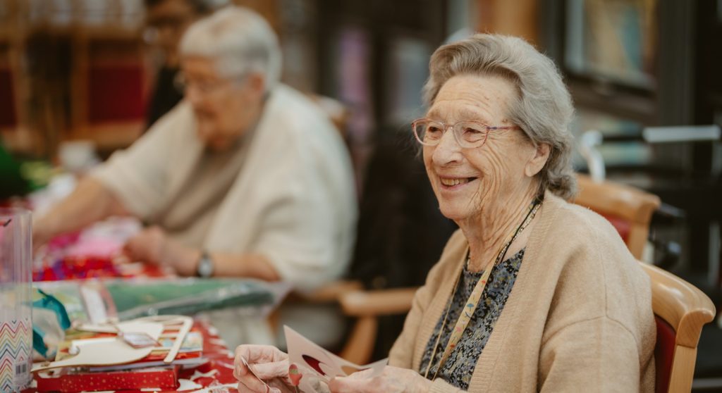 An elderly woman doing arts and crafts.