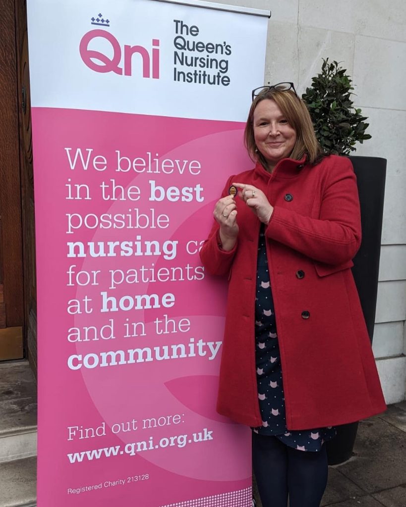 Teresa Chinn holding her Queen's Nurse badge at the ceremony.