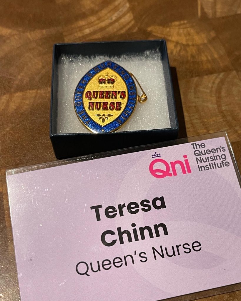 A Queen's Nurse badge next to a name tag that reads "Teresa Chinn: Queen's Nurse".