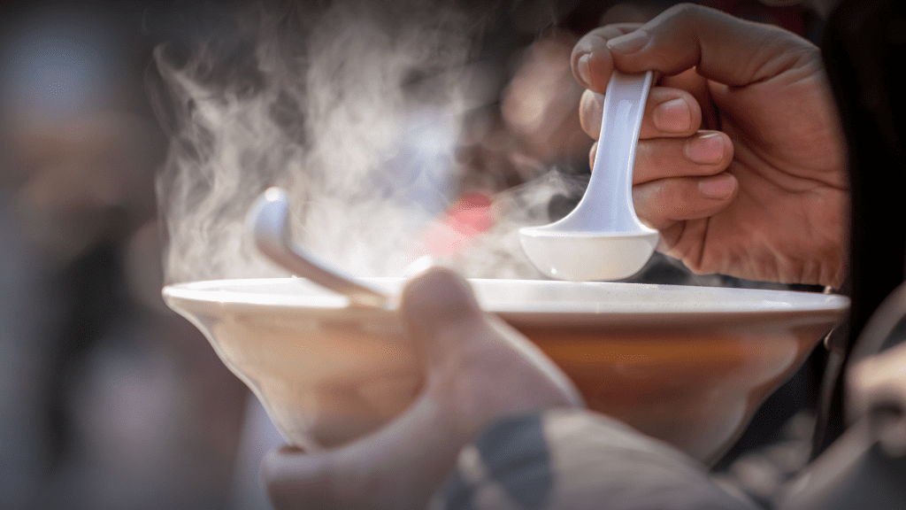 A warm bowl of soup with steam rising from it.