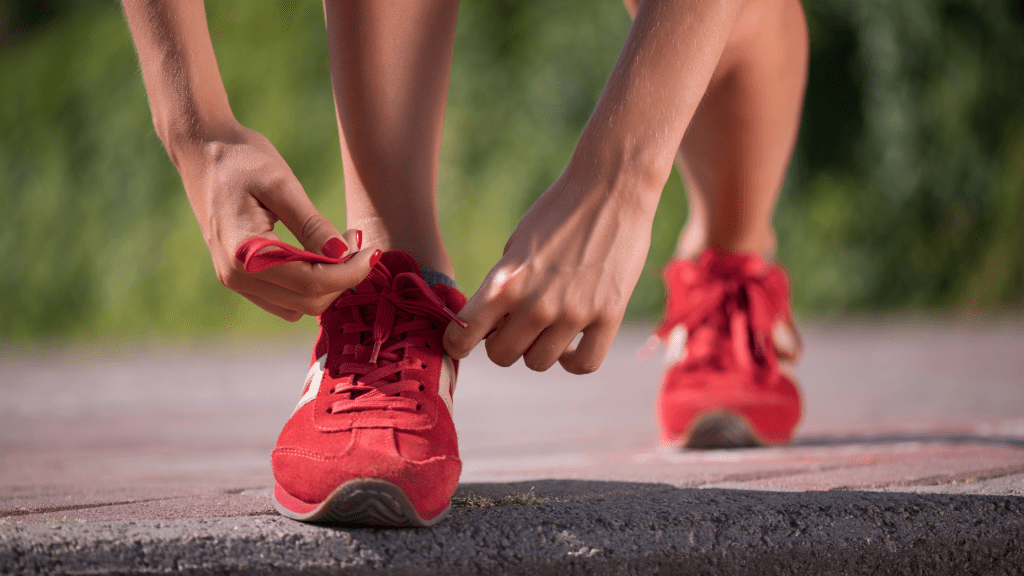 A person tying the laces on a pair of red trainers.