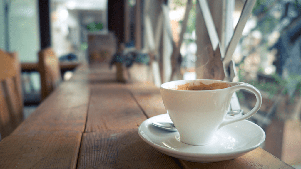 A white mug on a wooden table in a cafe.