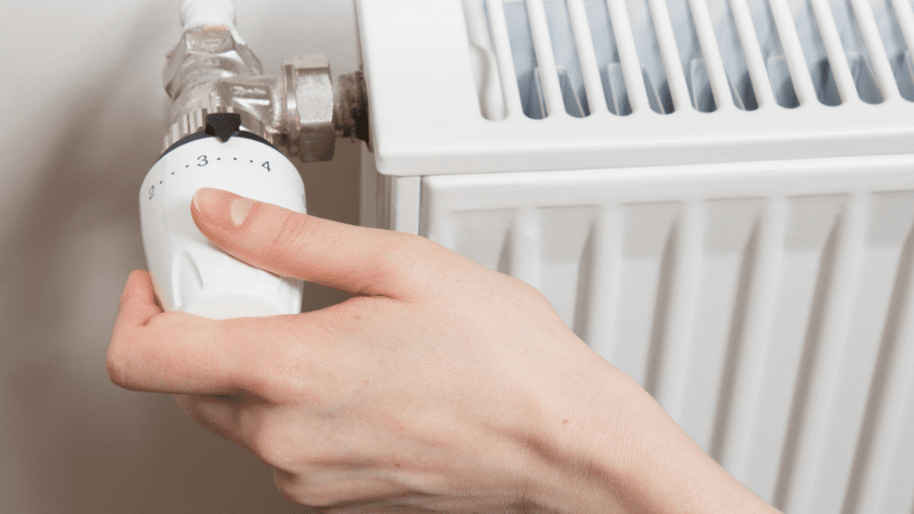 Close-up of a hand turning up a radiator.