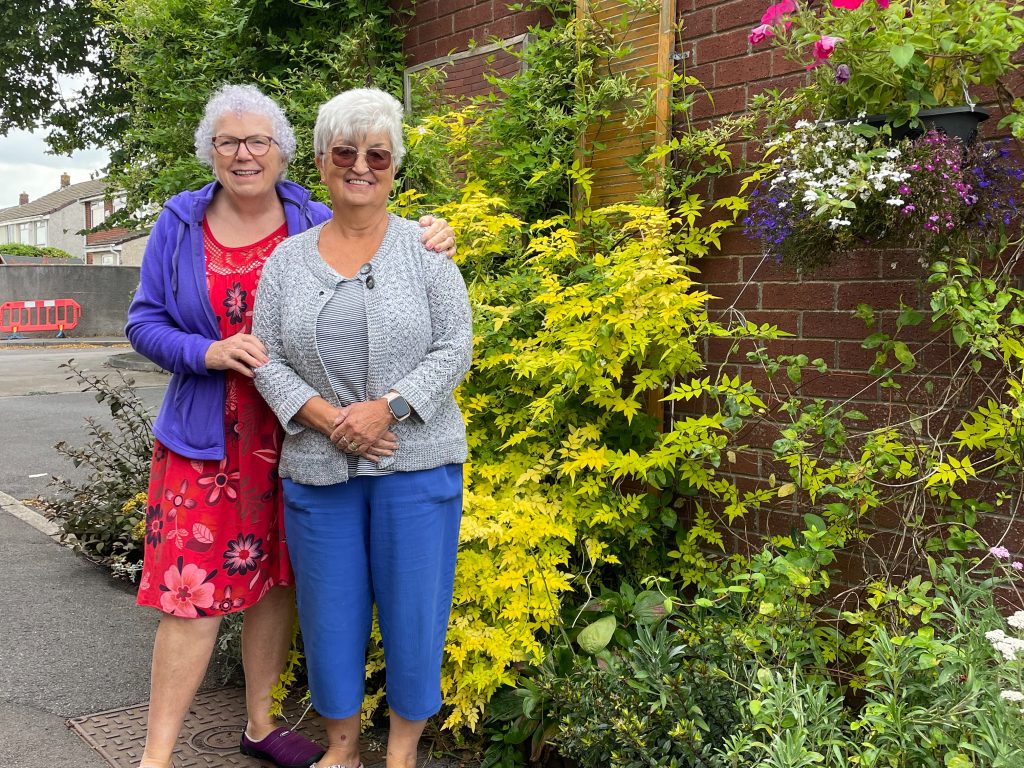 Two female tenants stand next to their entry for the housing gardening competition.